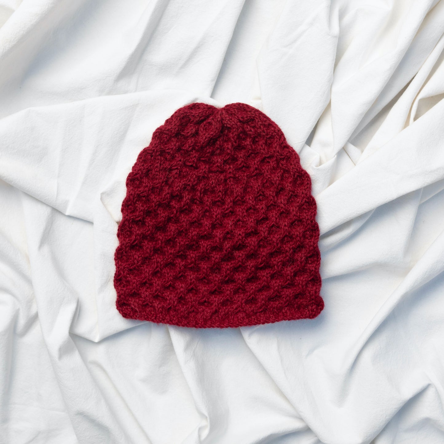 Burgundy coloured textured hand knitted beanie hat made from alpaca wool