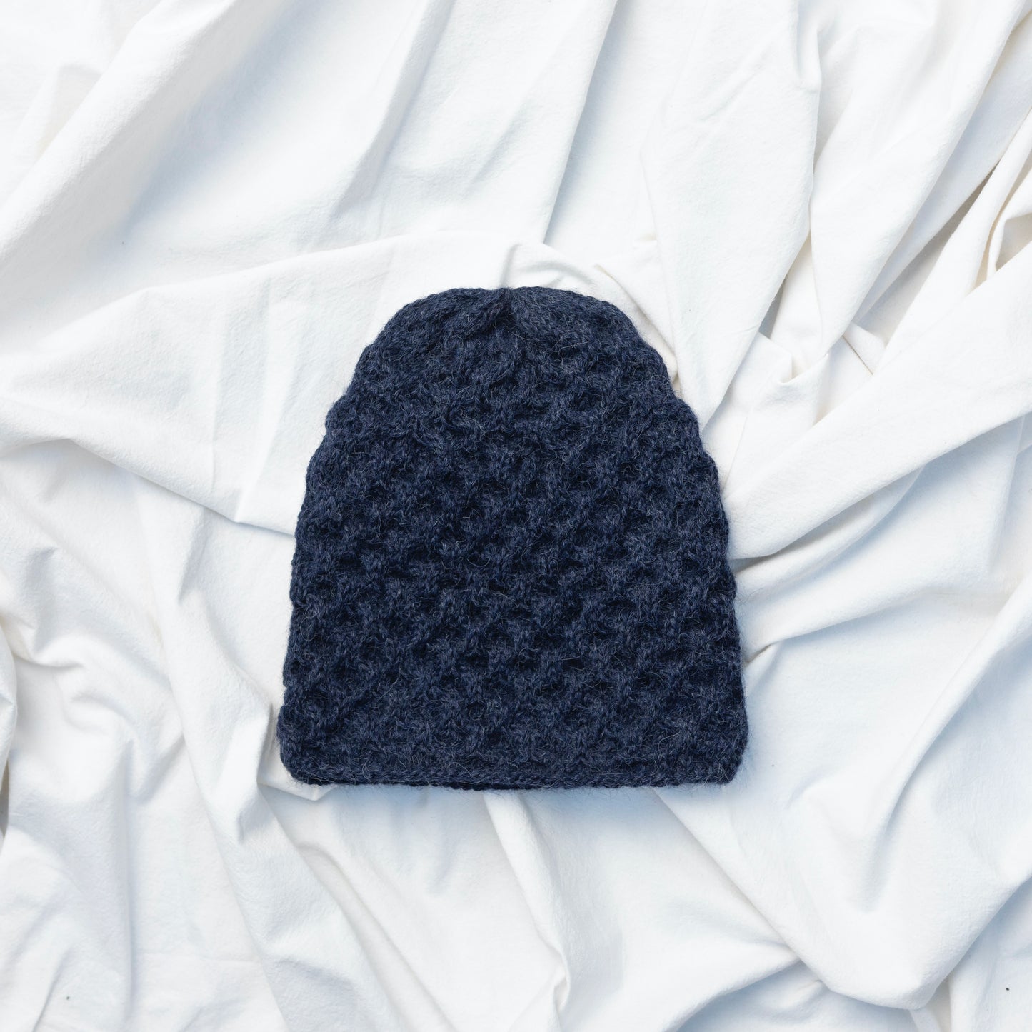 Textured hand knitted navy blue coloured beanie hat made from alpaca wool