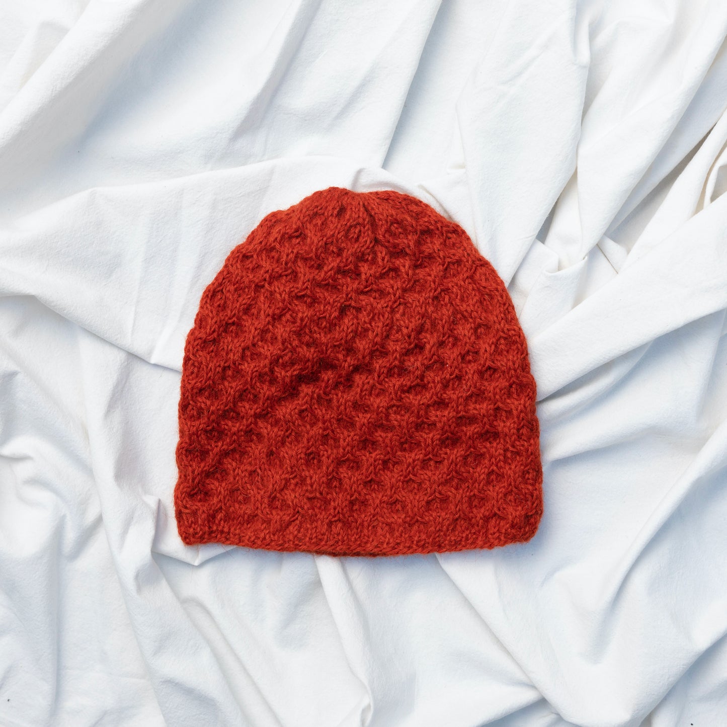 Textured hand knitted orange coloured beanie hat made from alpaca wool
