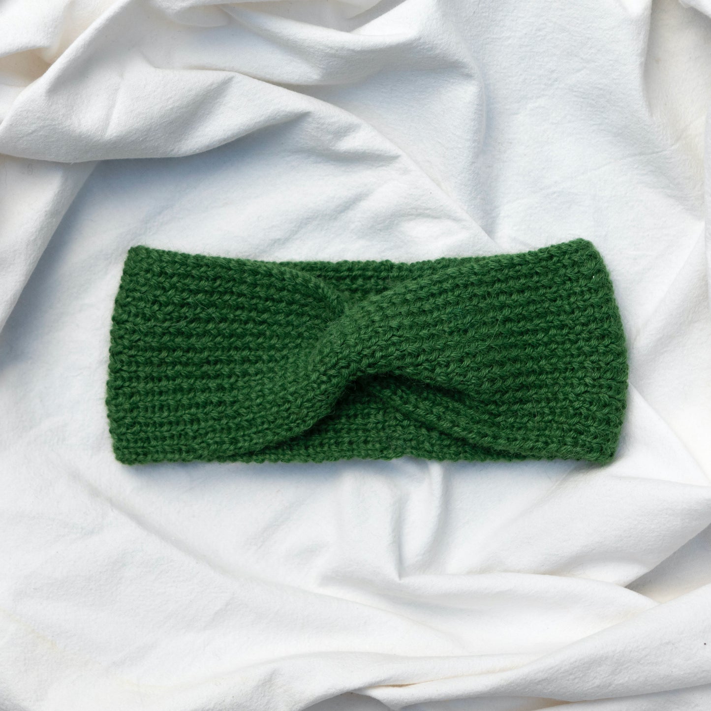 Cosy hand knitted green coloured headband with a cute twist at the front