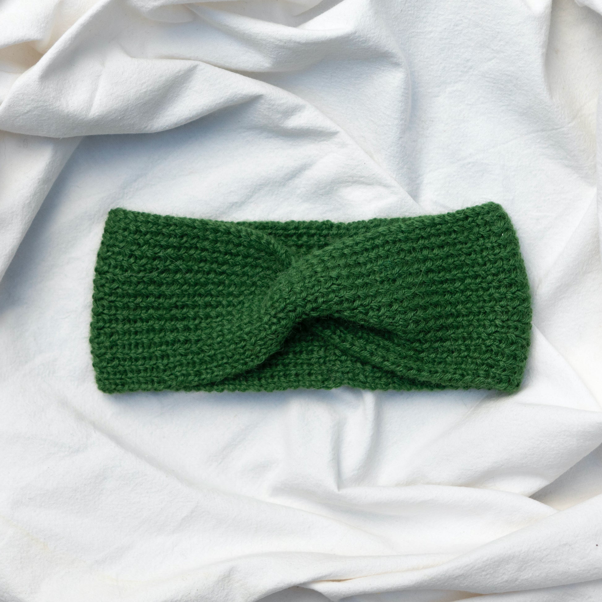 Cosy hand knitted green coloured headband with a cute twist at the front
