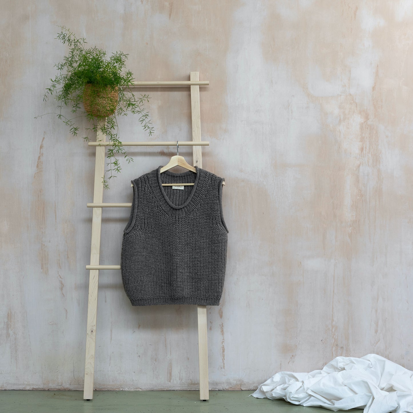 Brown coloured highland wool hand knitted vest hanging on ladder
