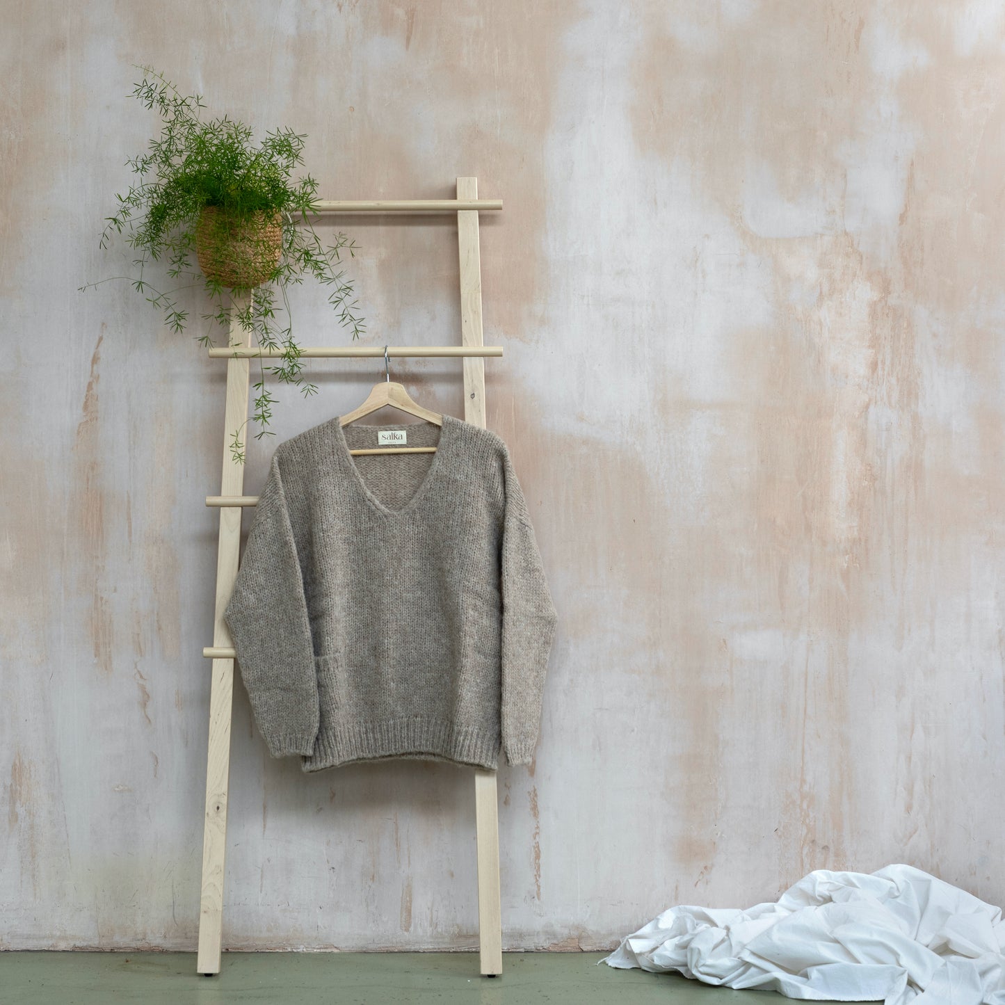 Warm v-neck sweater, beige colour, long sleeve, displayed on a ladder