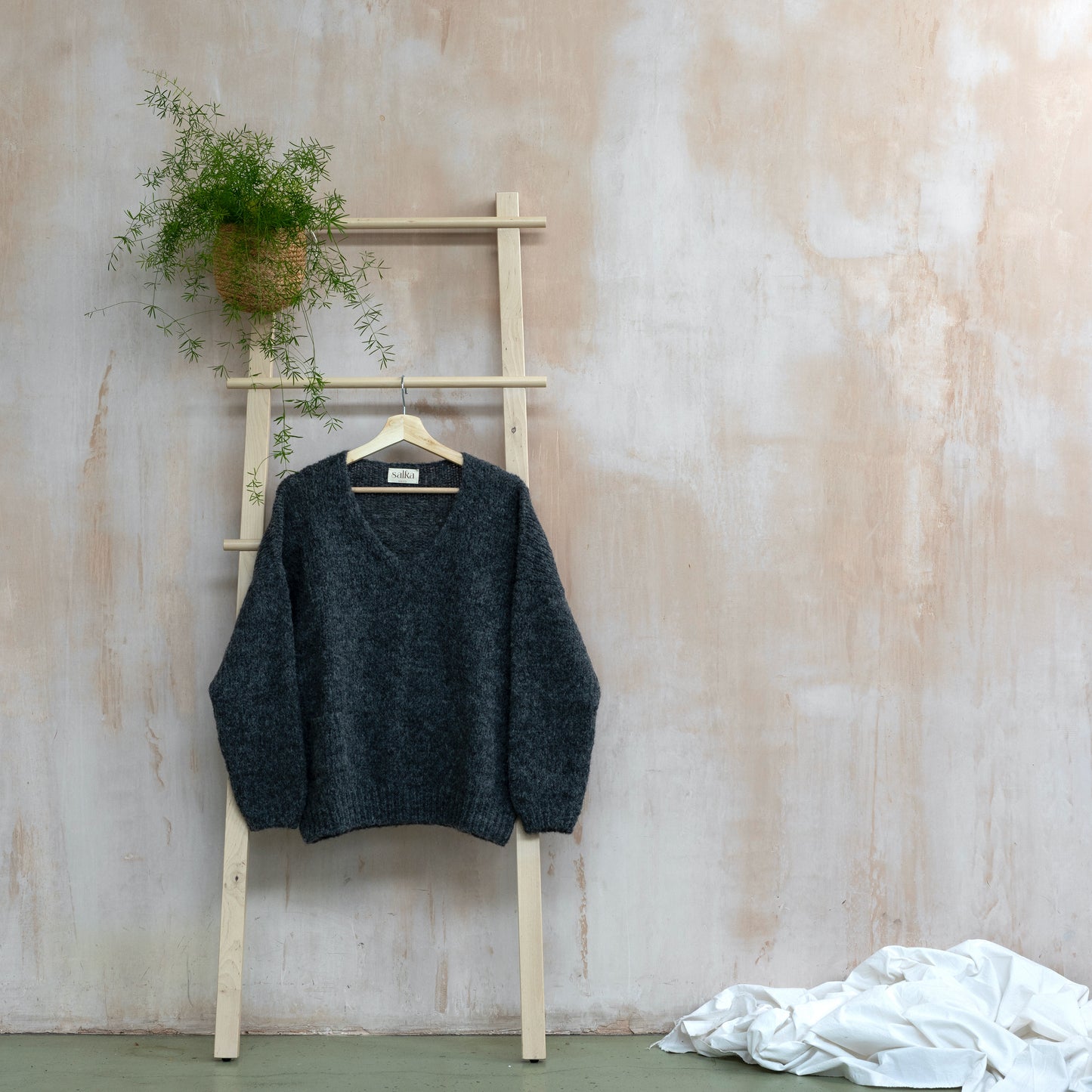 Warm v-neck alpaca sweater, dark grey colour, long sleeves, displayed on a ladder