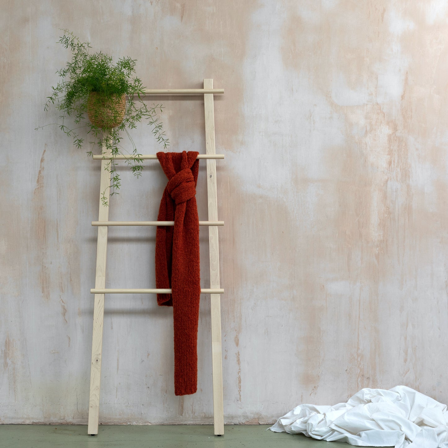 Chunky supersoft knitted scarf in orange colour hanging from wooden ladder