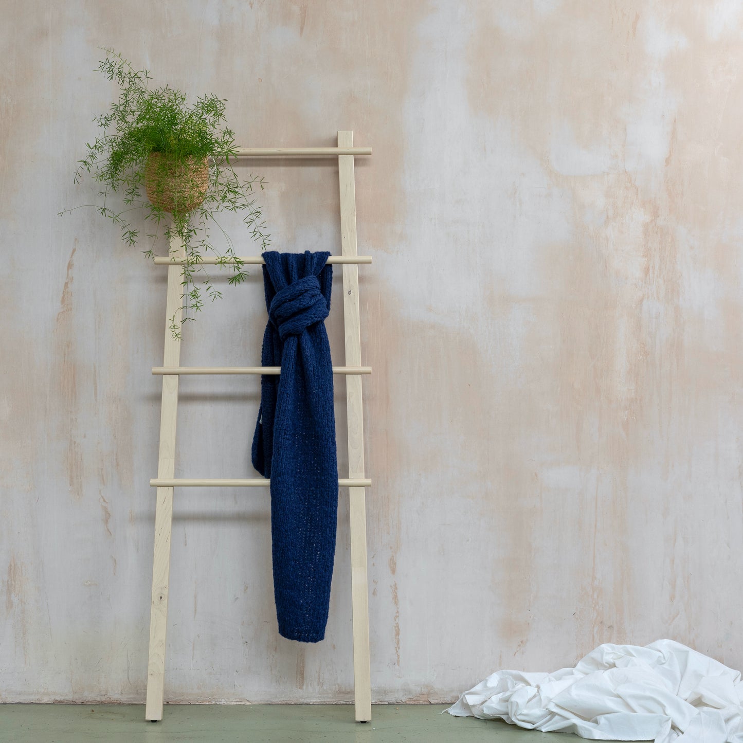 Deep navy blue coloured chunky scarf in super soft alpaca wool hanging from wooden ladder