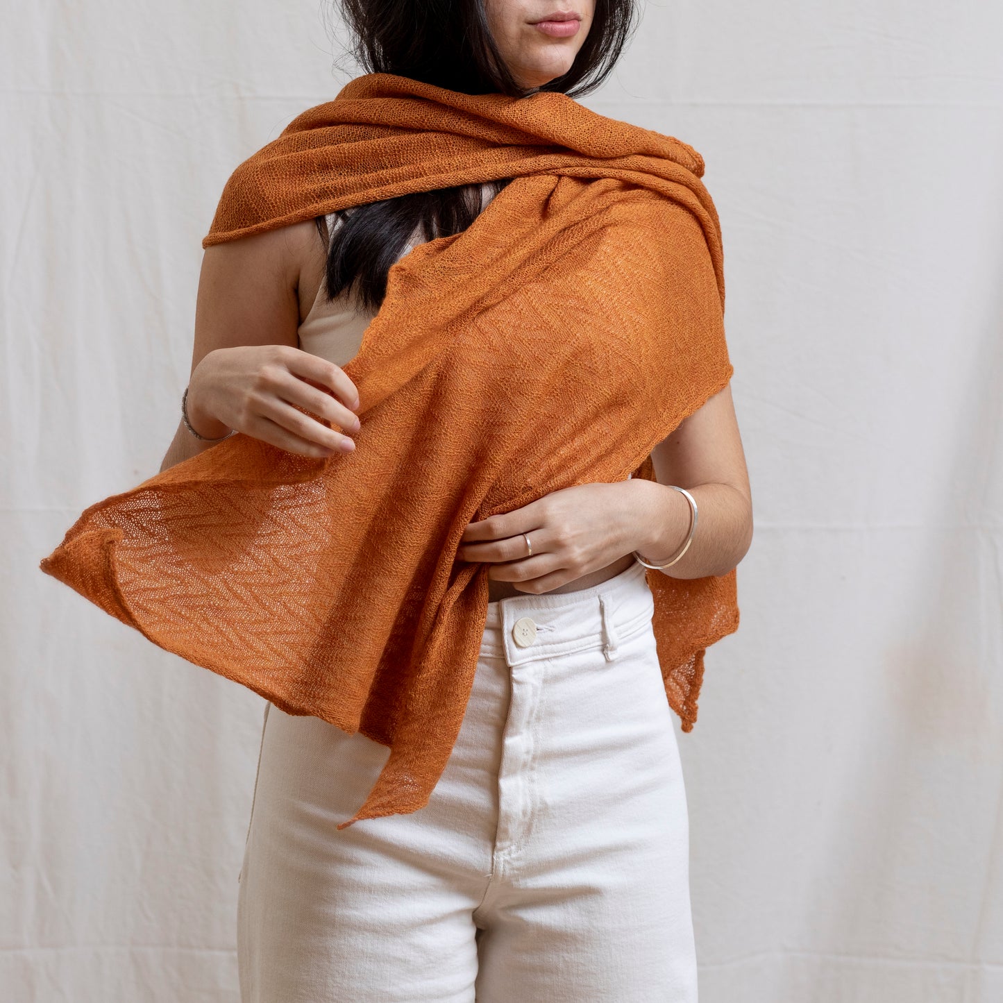 Woman wearing soft-orange coloured lightweight and delicately woven scarf. Hand-made by artisans.