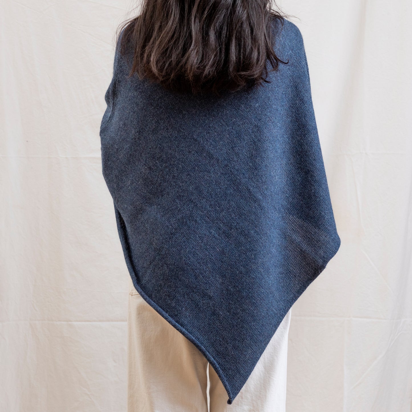 Woman wearing dark blue alpaca wool lightweight poncho.