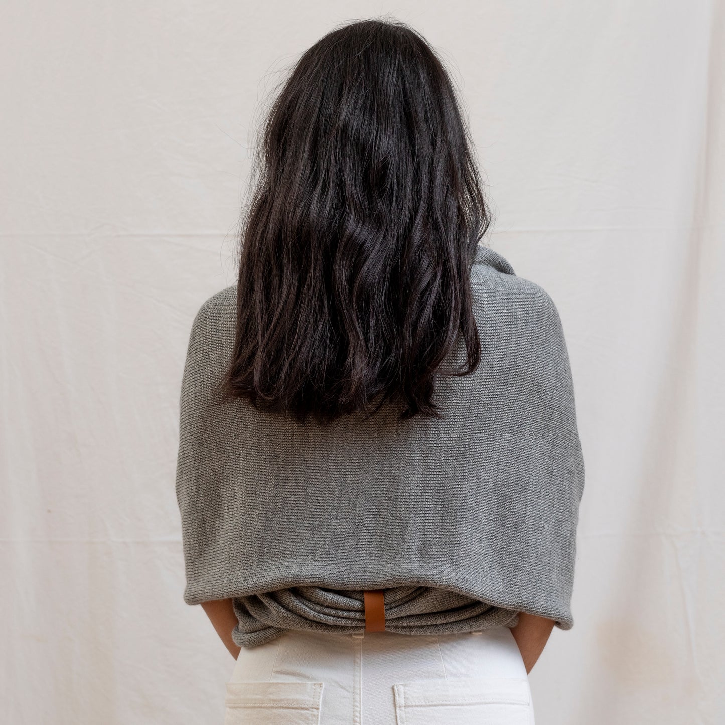 Woman wearing stone coloured luxury infinity scarf as a shrug with leather strap detail.