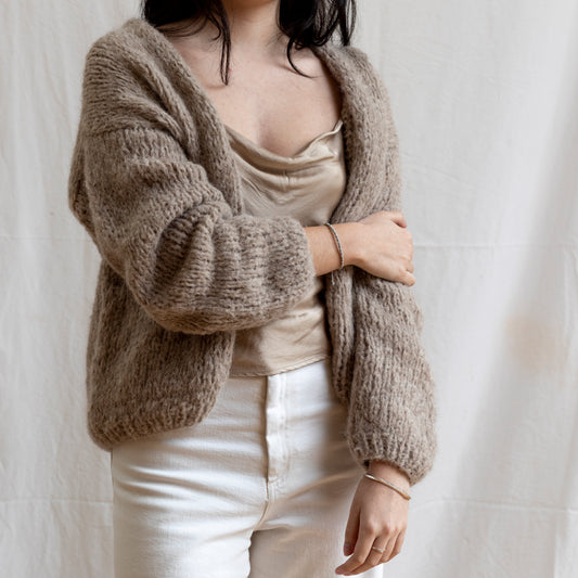 Woman wearing sand coloured knitted alpaca wool cardigan. Super-soft and cosy.