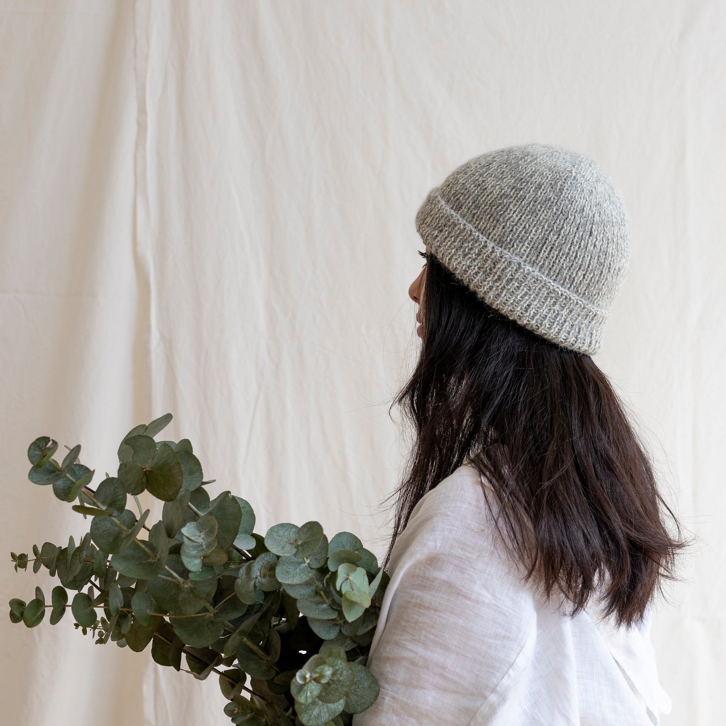 Woman wearing soft and luxurious alpaca knit fisherman's beanie in color stone.