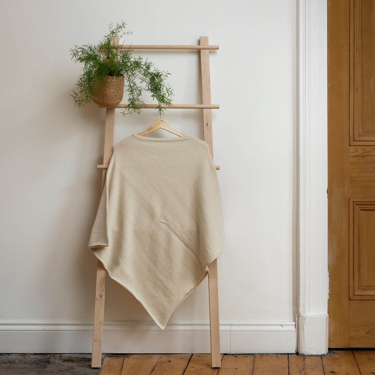 Lightweight texture and natural coloured, purely alpaca wool lightweight poncho hanging from wooden steps.