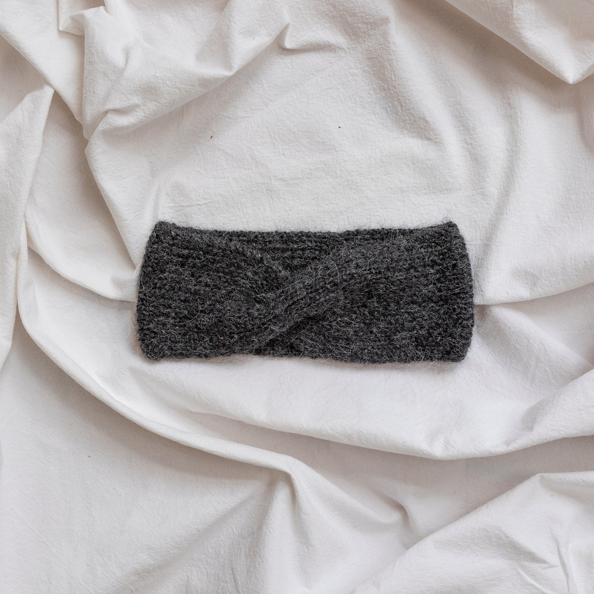 Cosy hand-knitted charcoal coloured headband with a cute twist at the front.