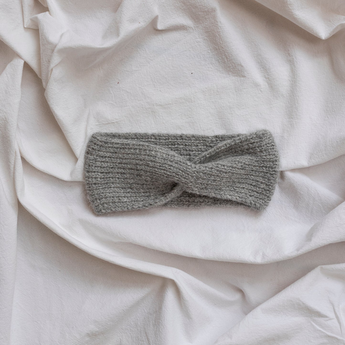 Cosy hand-knitted stone coloured headband with a cute twist at the front.