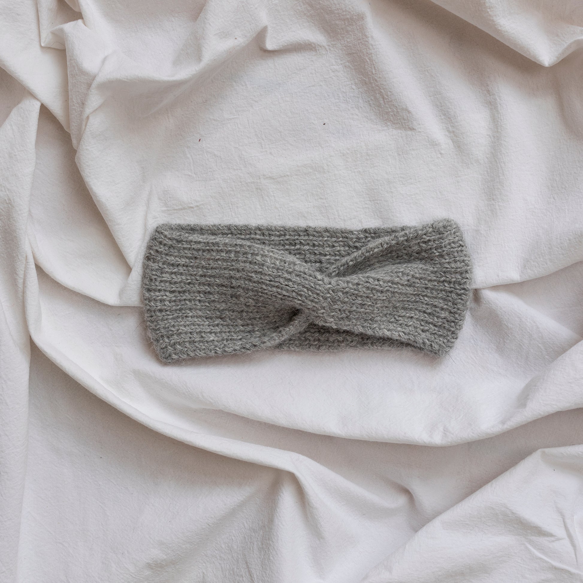 Cosy hand-knitted stone coloured headband with a cute twist at the front.