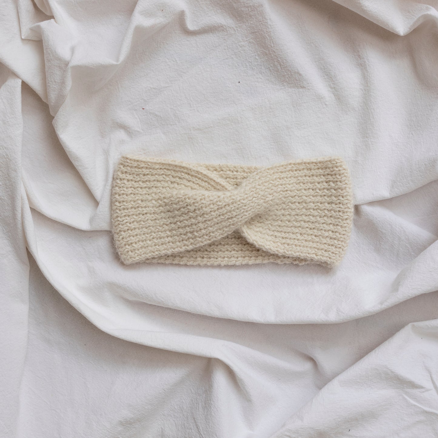 Cosy hand-knitted  natural coloured headband with a cute twist at the front.