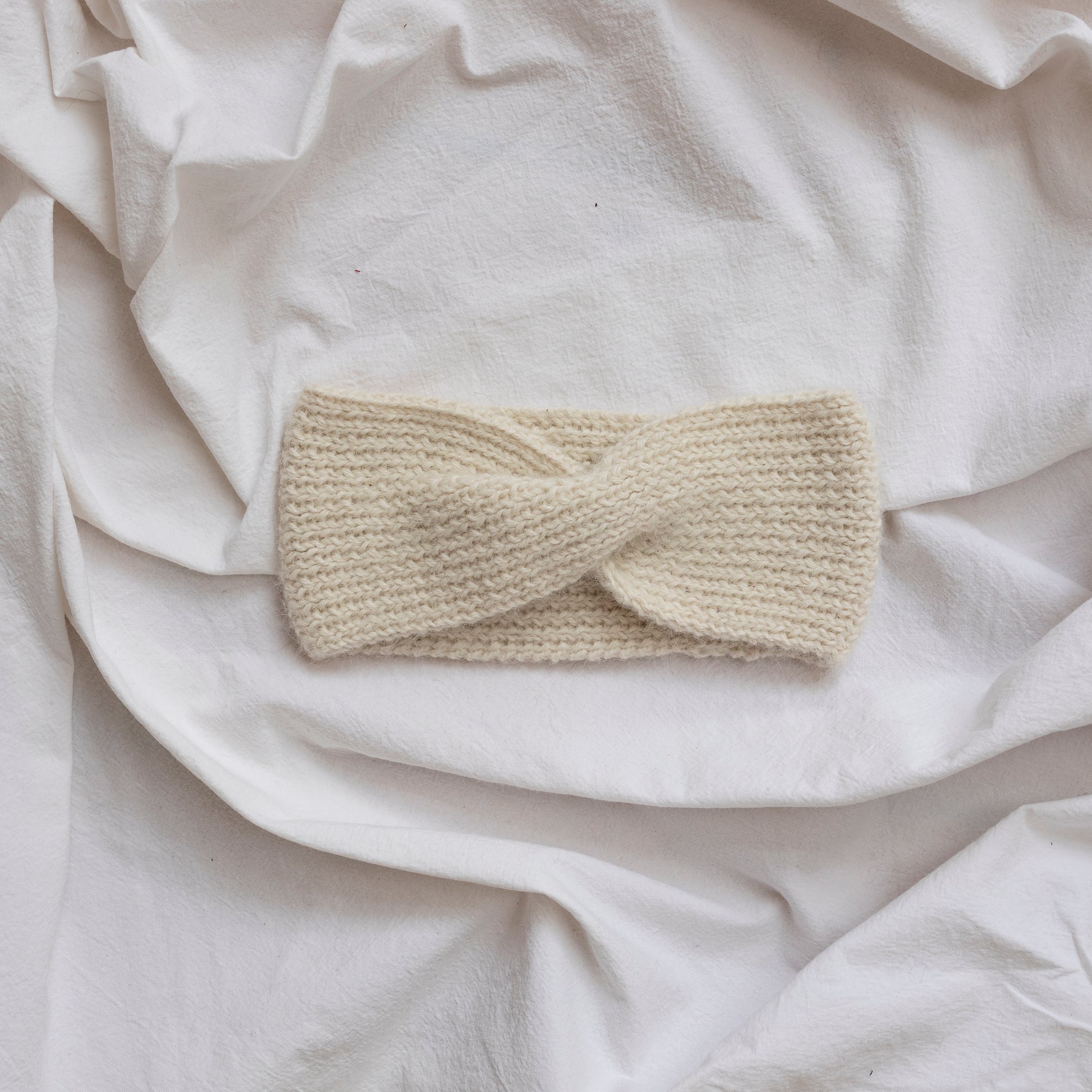 Cosy hand-knitted  natural coloured headband with a cute twist at the front.