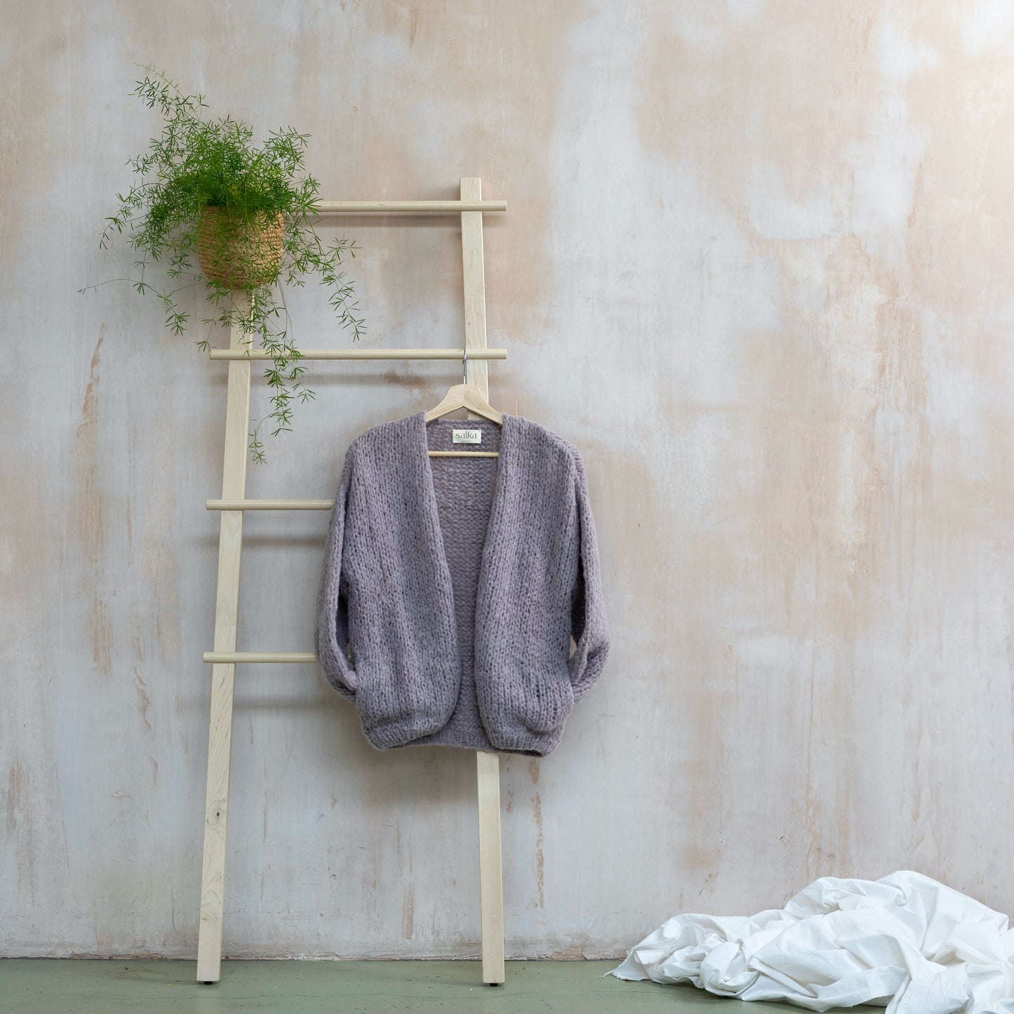 Lilac coloured hand knitted alpaca wool cardigan on wooden ladder. Super soft and cosy.