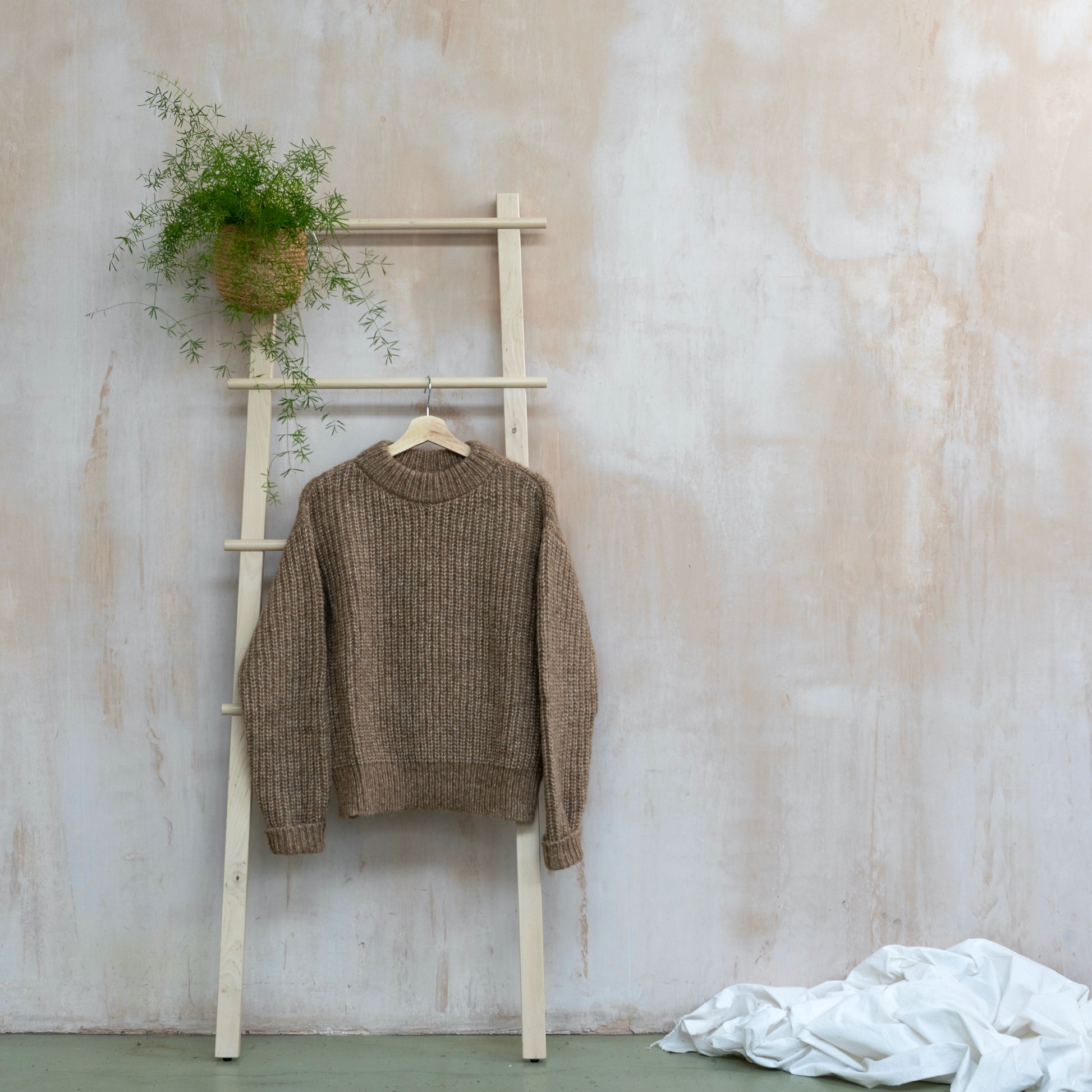 Round neck chunky knit sweater, alpaca and pima cotton, camel colour, displayed on a ladder