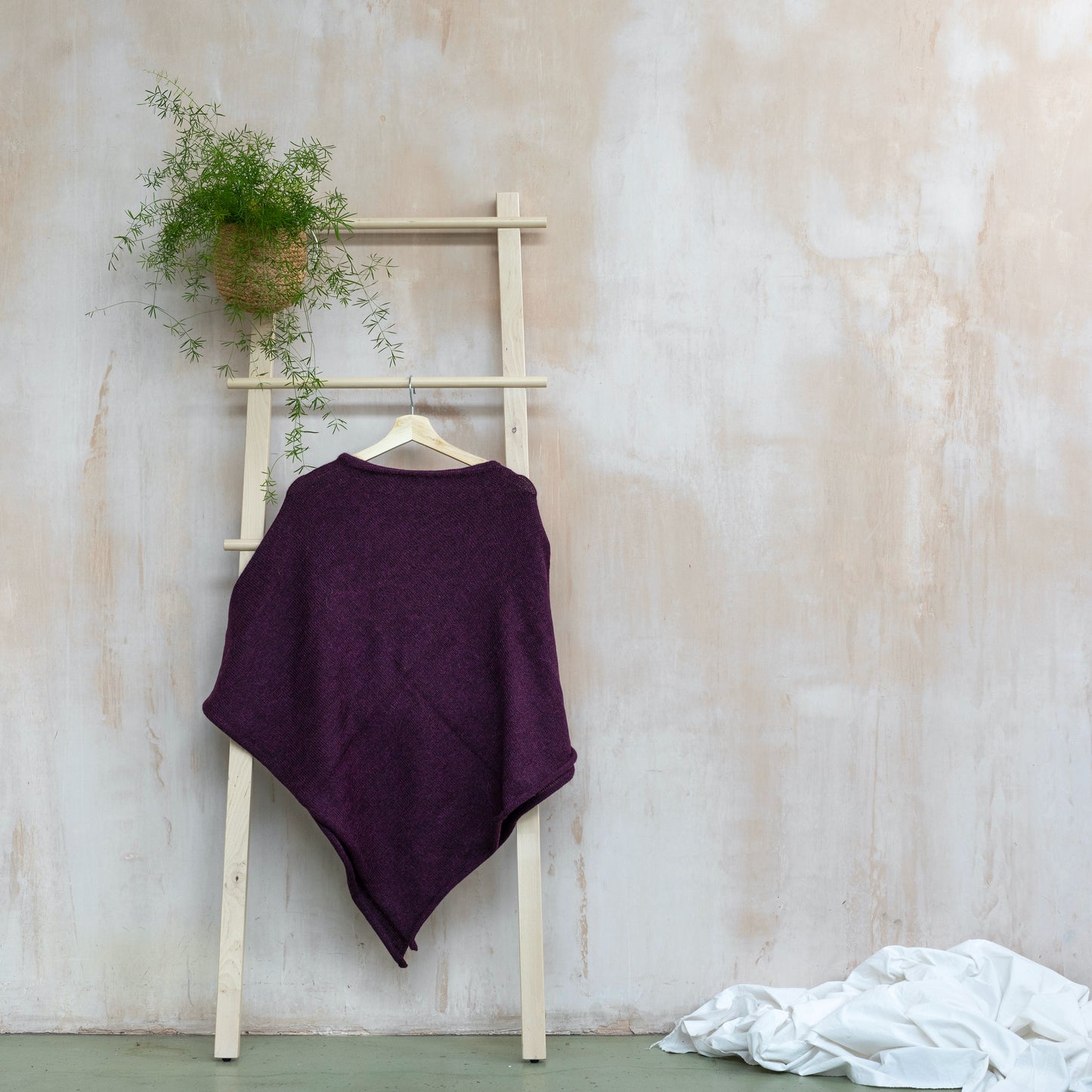 Lightweight texture purple coloured pure wool alpaca poncho hanging from wooden ladder