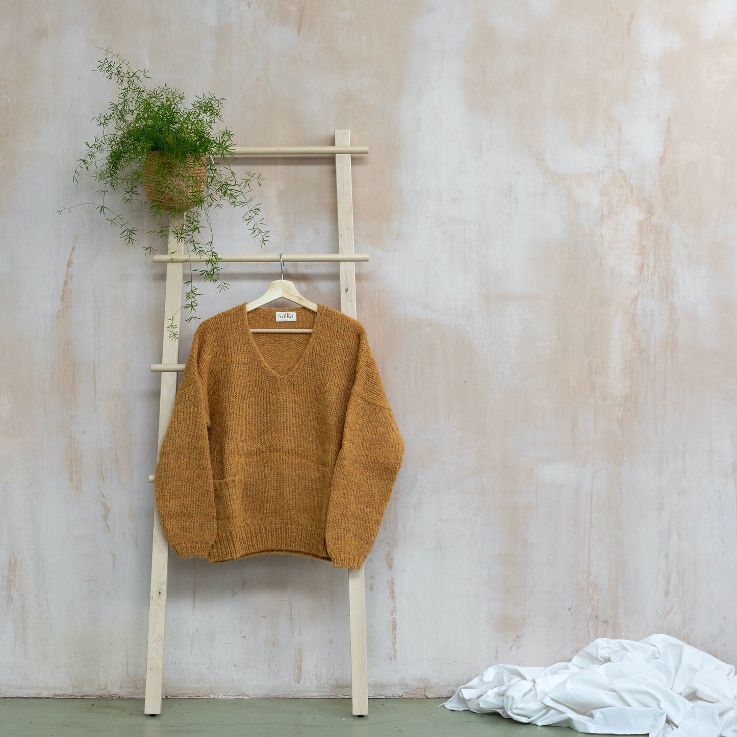 Warm v-neck alpaca sweater, yellow colour, long sleeve, displayed on a ladder
