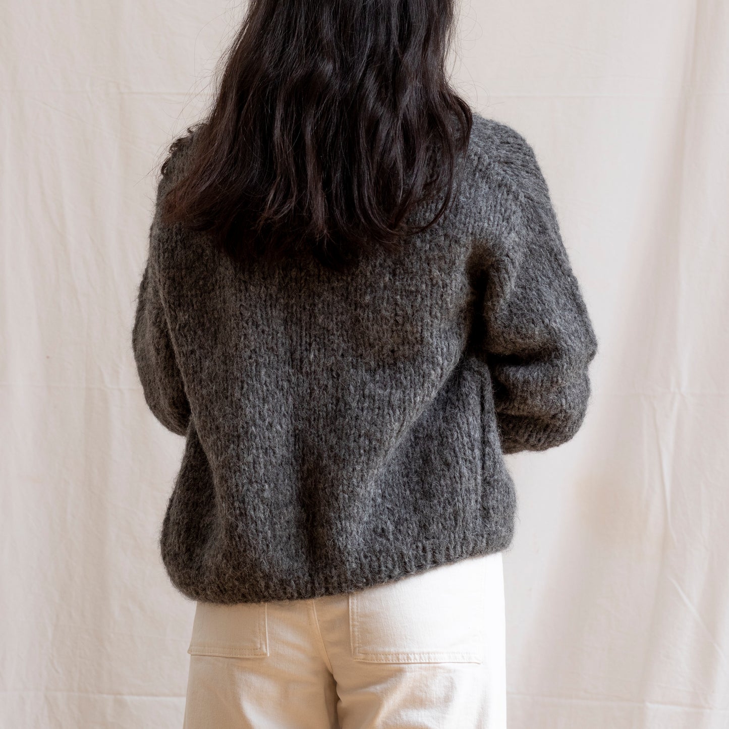 Woman wearing charcoal coloured knitted alpaca wool cardigan. Super-soft and cosy.