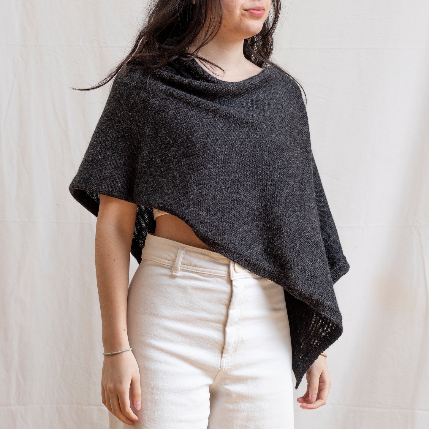 Woman wearing asymmetrical dark grey luxury knitted poncho.