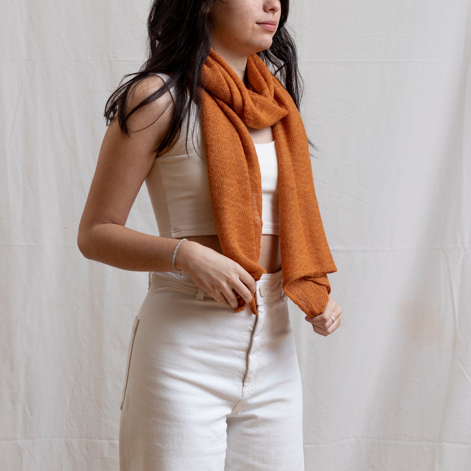 Woman wearing soft-orange coloured lightweight and delicately woven scarf. Hand-made by artisans.  