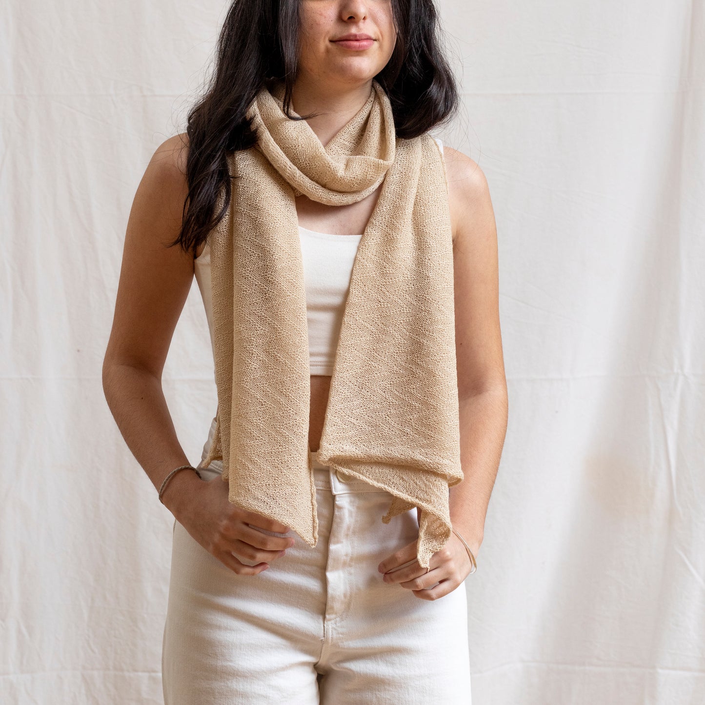 Woman wearing sand coloured lightweight and delicately woven scarf. Hand-made by artisans.  