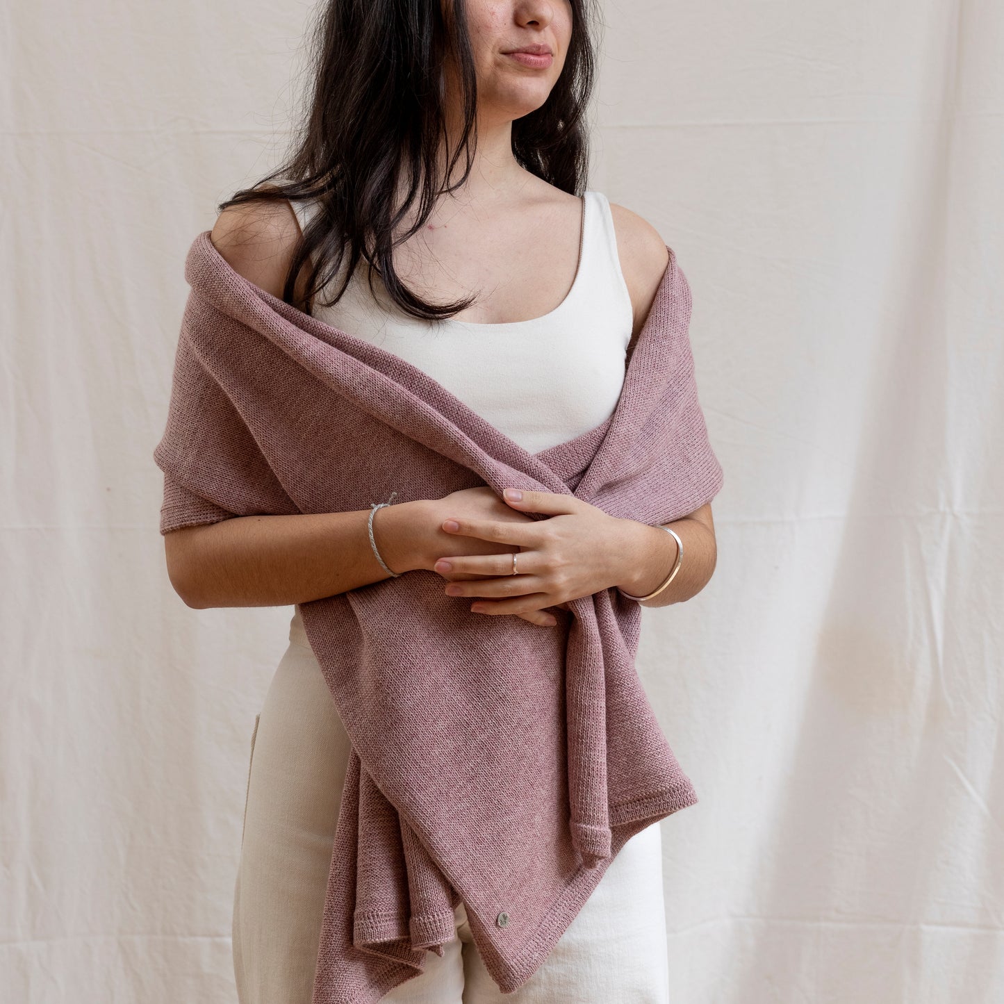 Woman wearing a luxurious alpaca wool one-of-a-kind pink scarf, hand-knitted by artisans. 