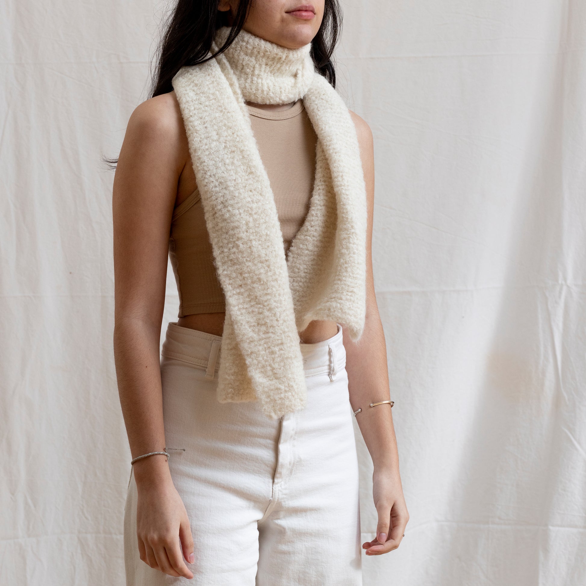 Woman wearing a luxury, boucle and natural coloured lightweight scarf. 
