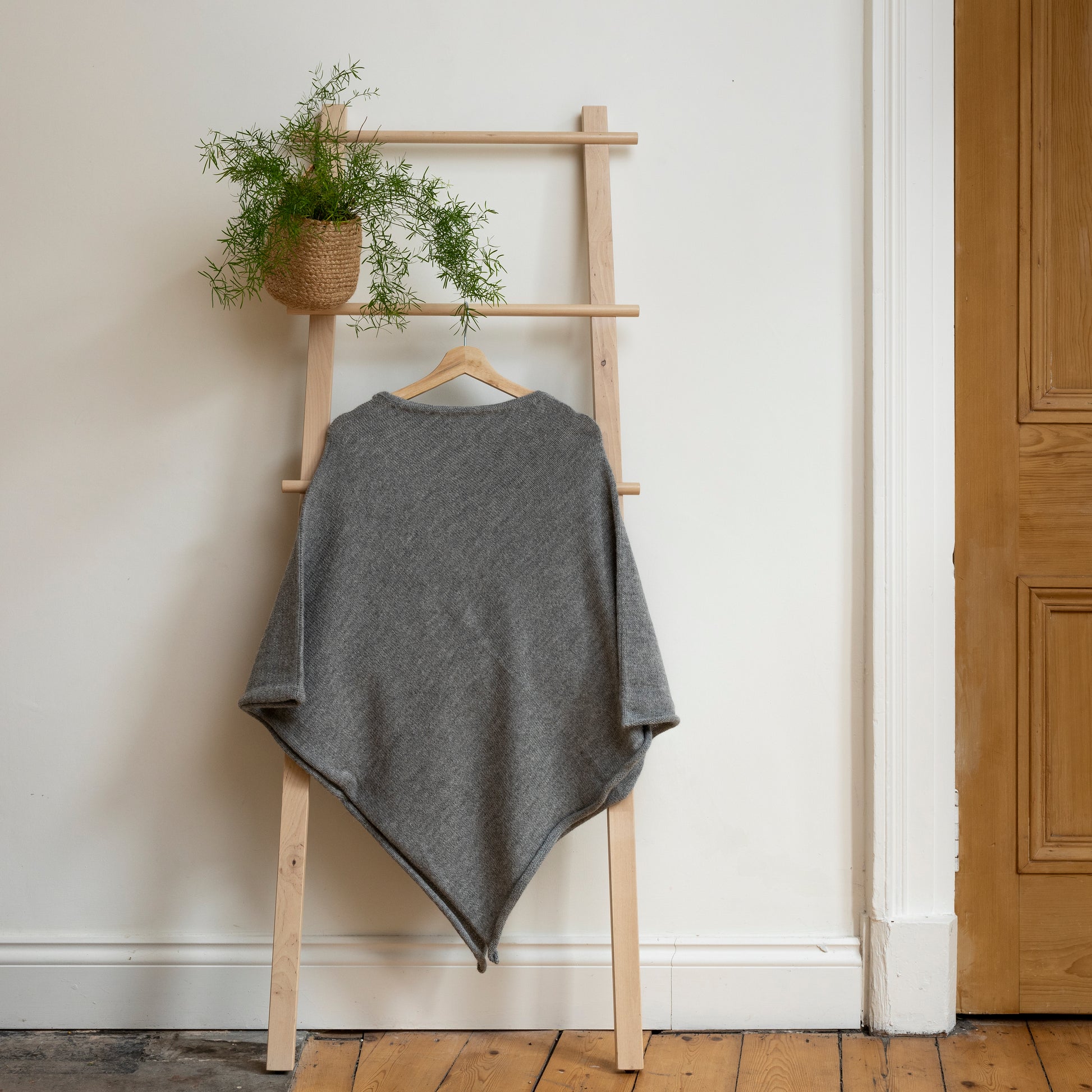 Lightweight texture and stone coloured, purely alpaca wool lightweight poncho hanging from wooden steps.