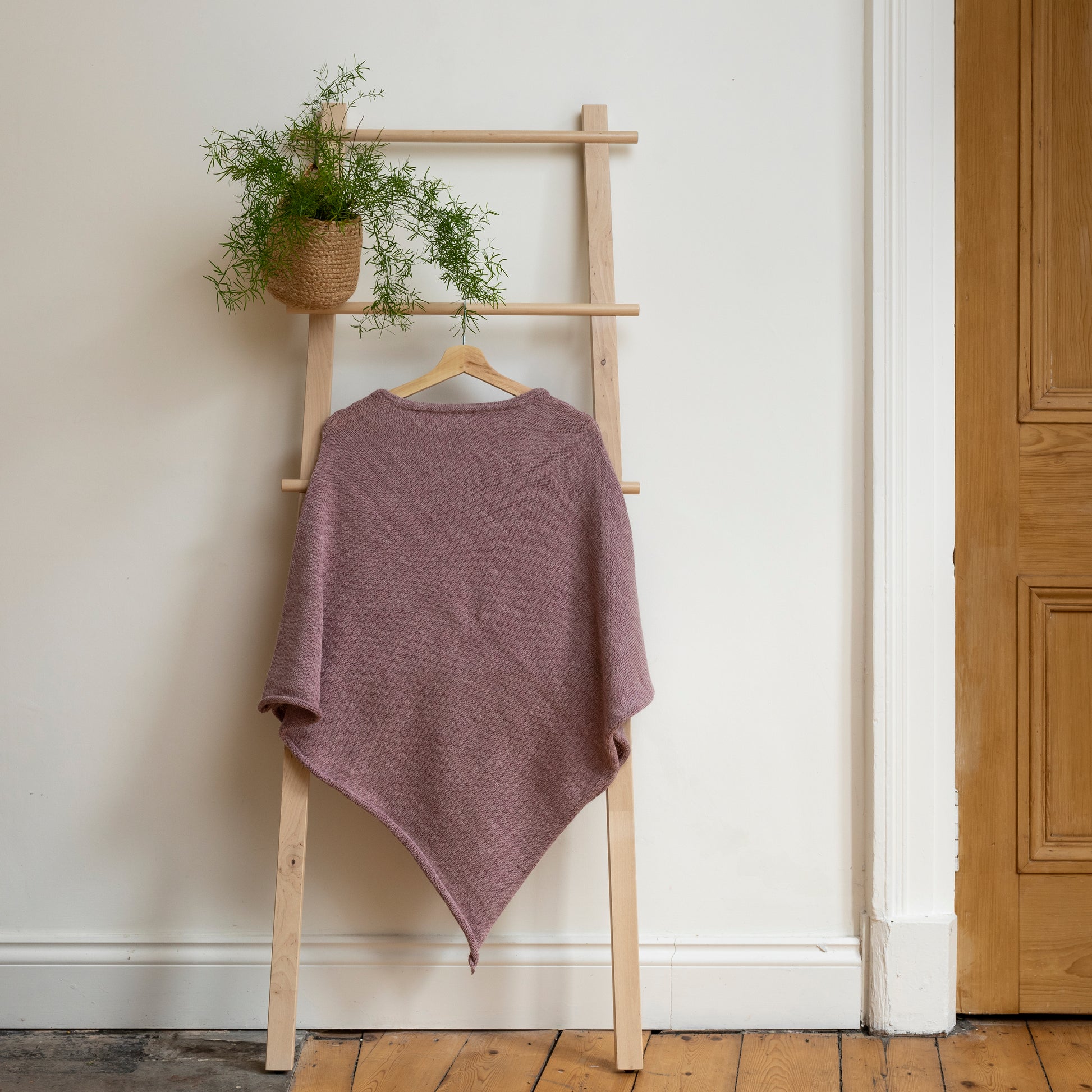 Lightweight texture and rose coloured, purely alpaca wool lightweight poncho hanging from wooden steps.
