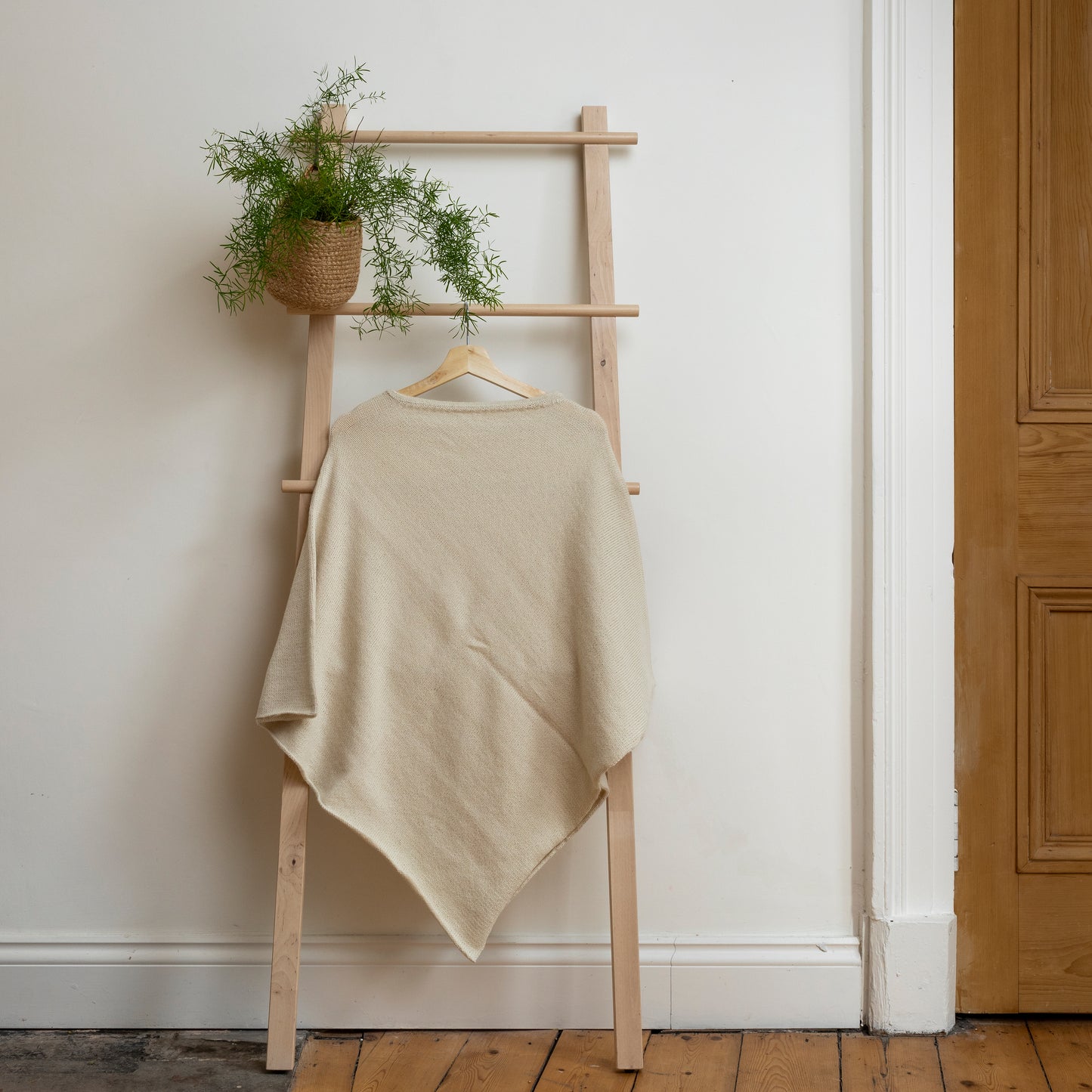 Lightweight texture and natural coloured, purely alpaca wool lightweight poncho hanging from wooden steps.