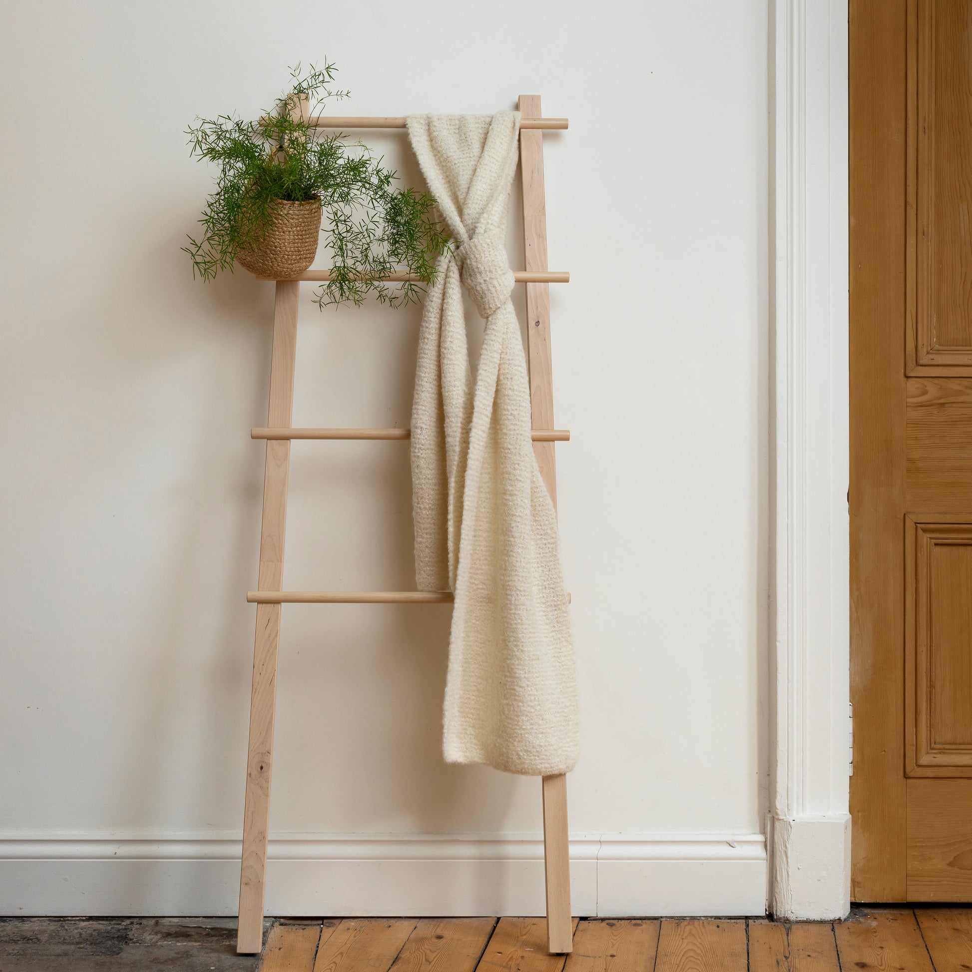 Beautiful, one of a kind white hand-knitted scarf displayed on wooden ladder