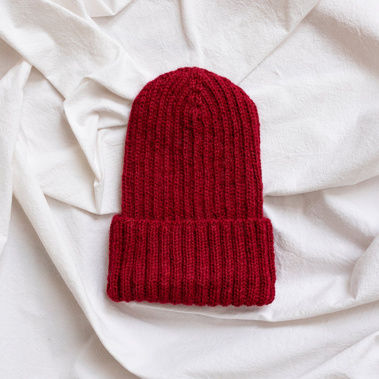 Burgundy coloured soft beanie with rib detail made from alpaca wool.