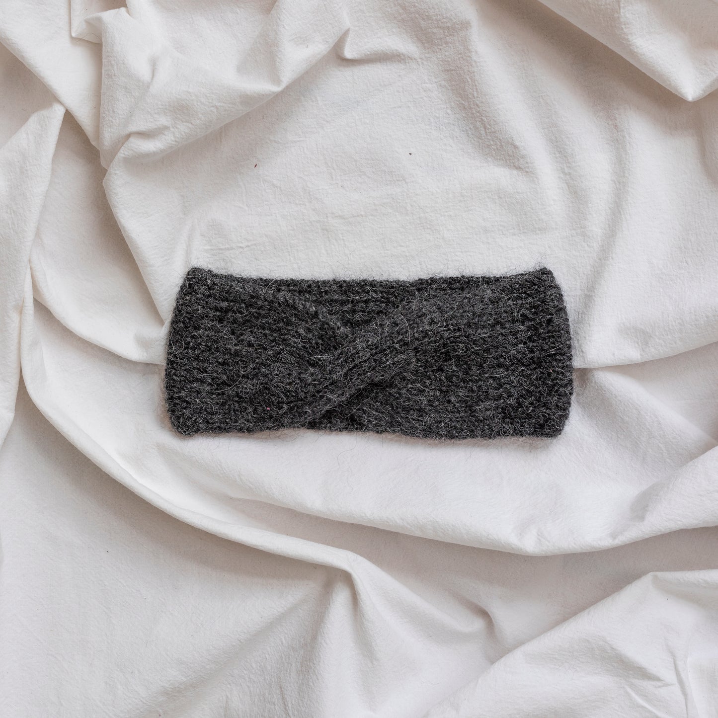Cosy hand-knitted charcoal coloured headband with a cute twist at the front. 